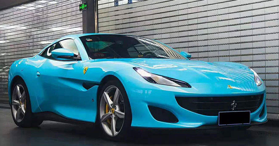 masina bleu deschis lucios parcata langa un zid