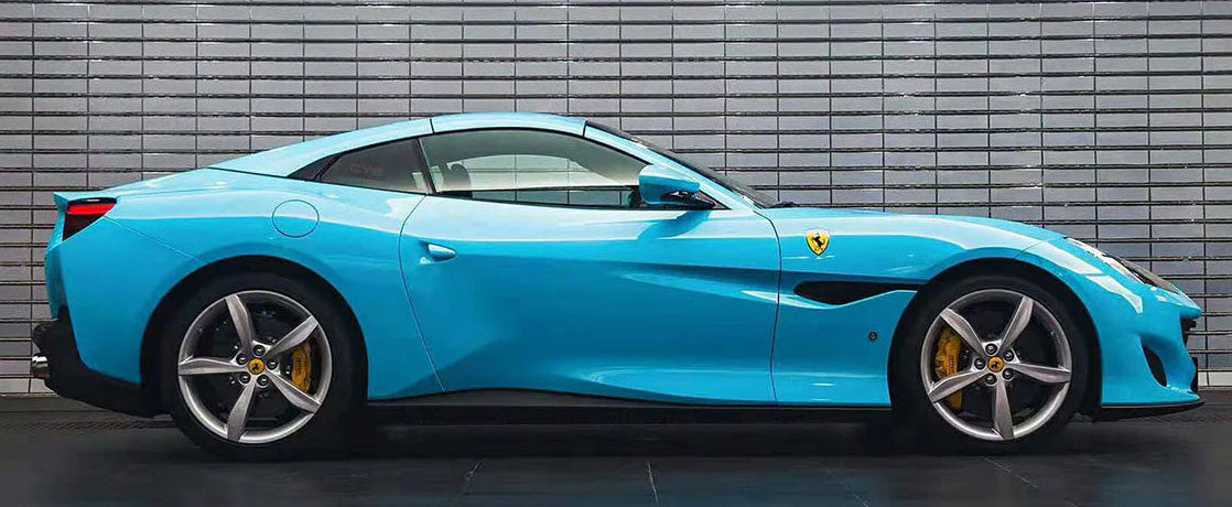 masina bleu deschis lucios parcata langa un zid