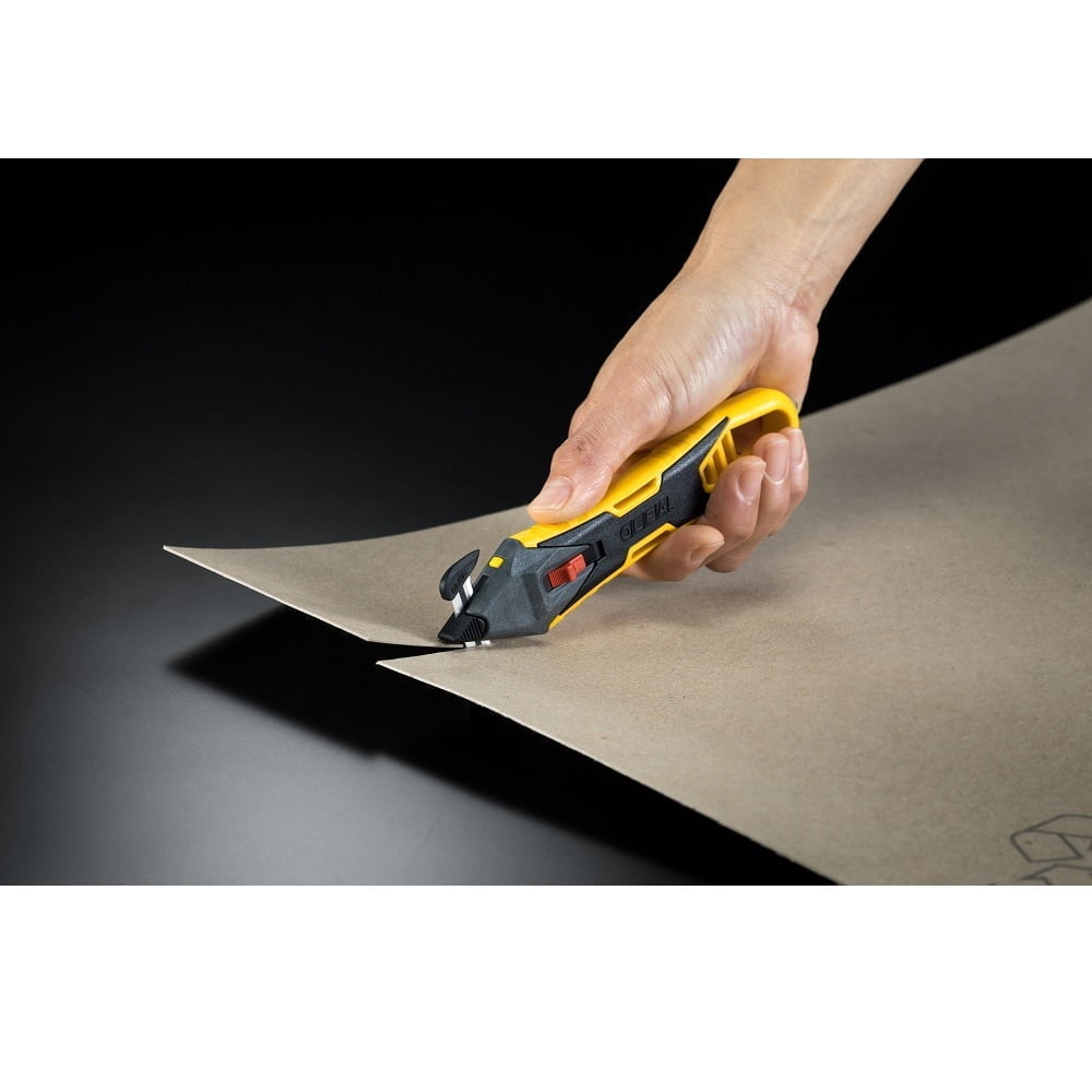 mana cu un cutter galben cu cap de taiere schimbabil negru taie o bucata de carton