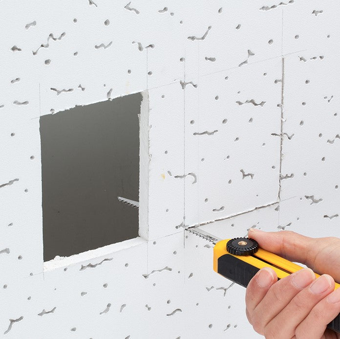 mana care taie o bucata de rigips alb cu un ajutorul unui cutter cu lama tip ferastrau