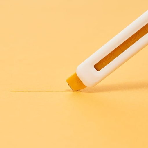 cutter alb cu interior galben si protectie a lamei taie o suprafata galbena