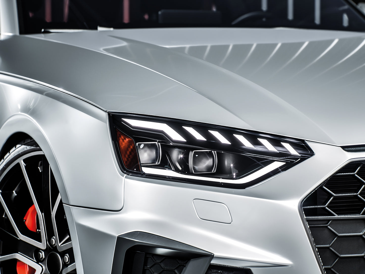 Prim-plan al farului frontal al unui SUV alb si al designului grilei cu lumini LED albe luminate.