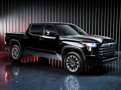 O camioneta neagra eleganta, cu accente cromate stralucitoare, parcata in fata unei perdele argintii metalice cu podea neagra reflectorizanta.