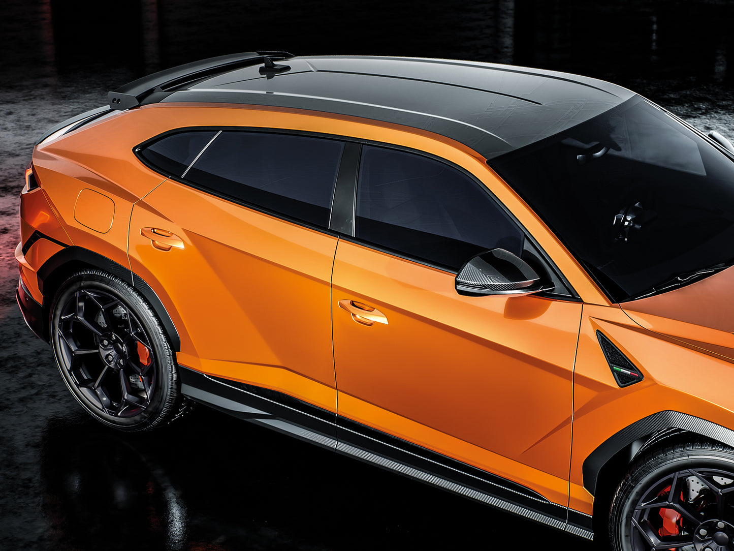O masina sport eleganta, portocalie, cu detalii negre, cu jantele din aliaj strălucitoare si geamurile fumurii vizibile parcata.