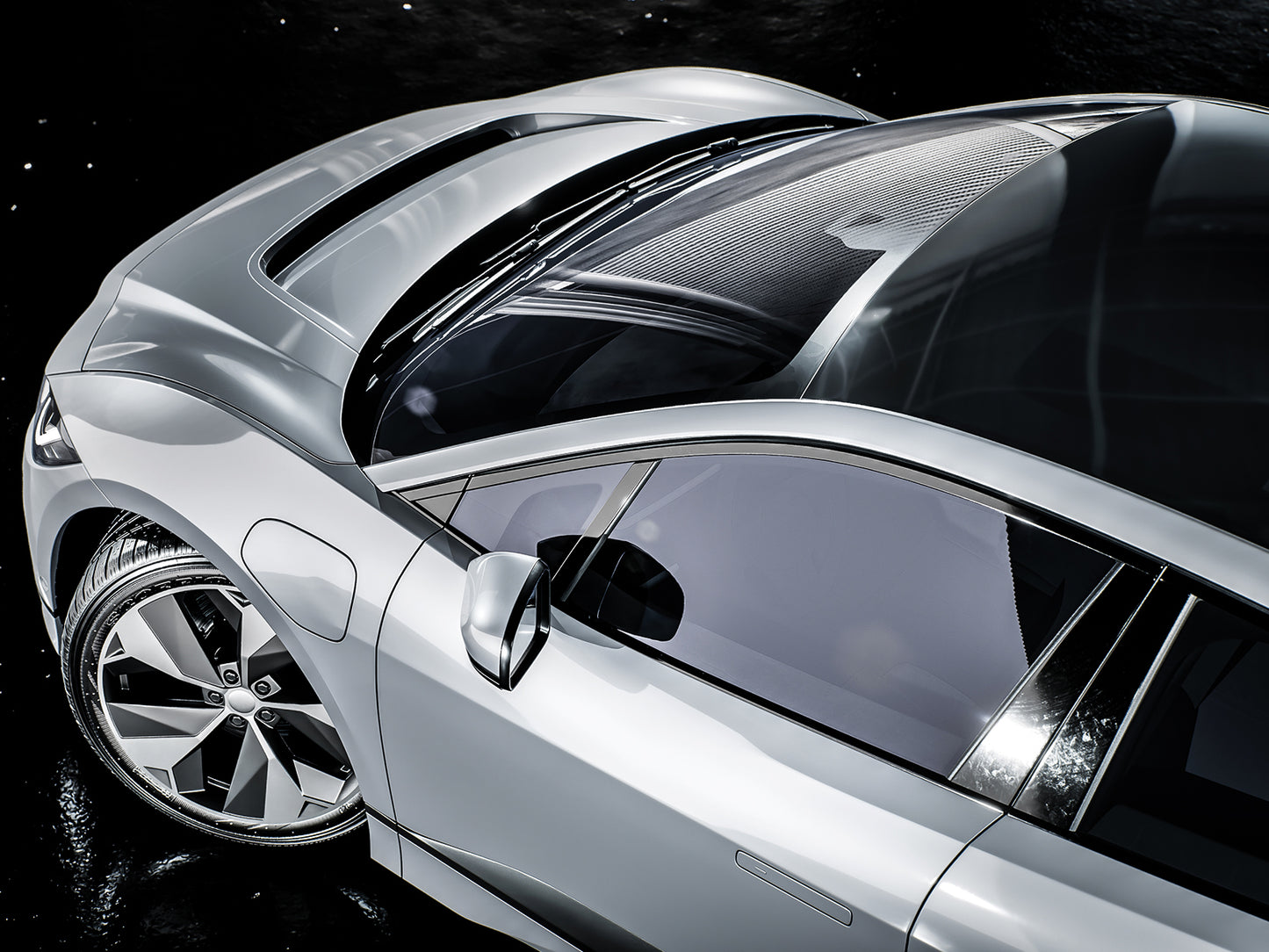 Prim-planul unei masini sport argintii care isi arata designul elegant si rotile stralucitoare, cu un cer intunecat si instelat in fundal.