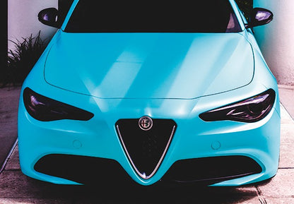 Vedere frontala a unei masini sport turcoaz, cu o grila triunghiulara distincta si faruri elegante